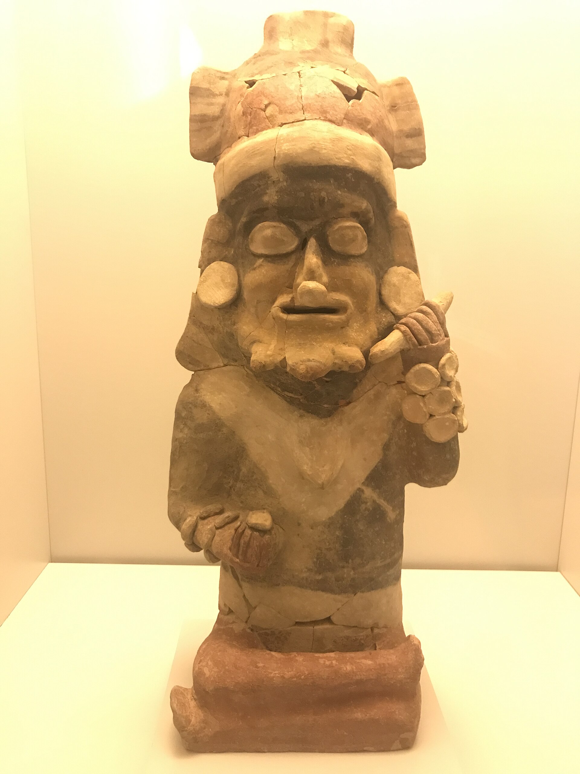 Figura de cerámica de la cultura Bahía que representa a un personaje principal sentado, con tocado y ornamentos