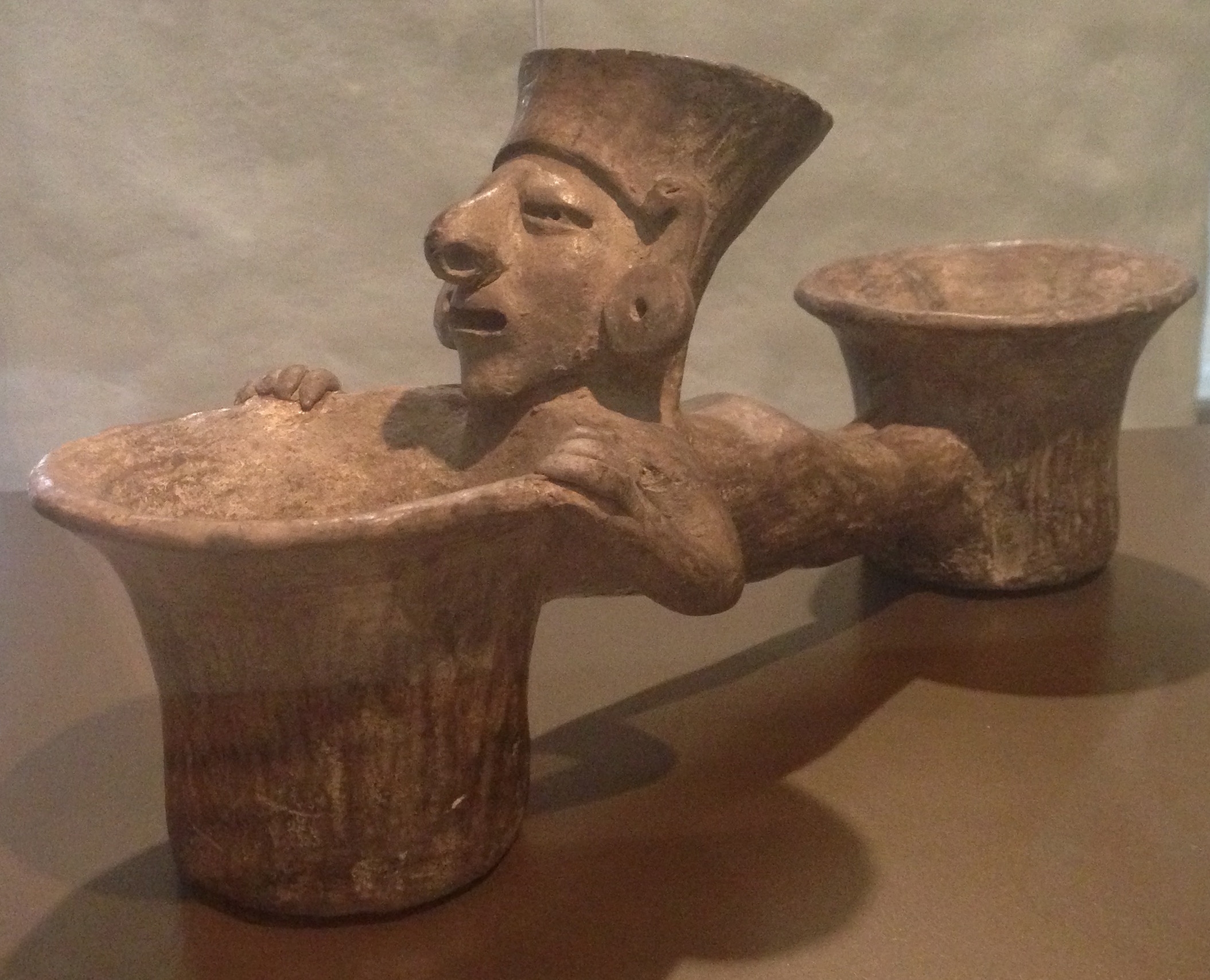 Escultura de cerámica manteño-huancavilca que representa a un hombre conectando dos vasijas